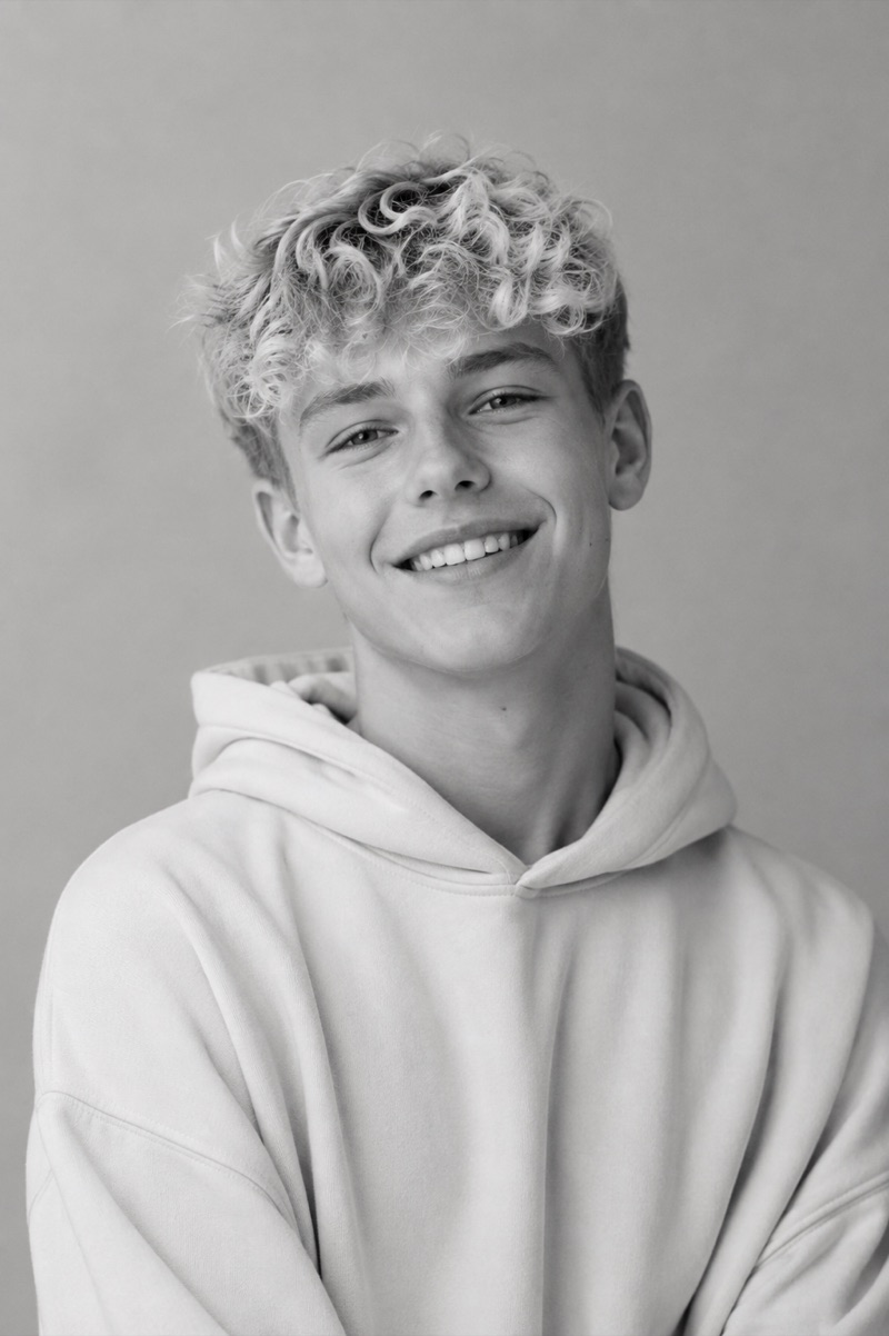 Porträt eines lächelnden Jugendlichen mit blonden Locken im Hoodie